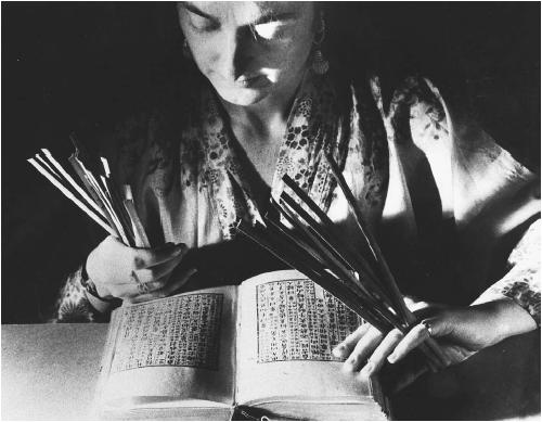 Woman consulting with the book I Ching and using fortune sticks. (FORTEAN PICTURE LIBRARY)