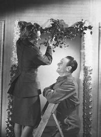 Man and woman  hanging mistletoe. (CORBIS CORPORATION)